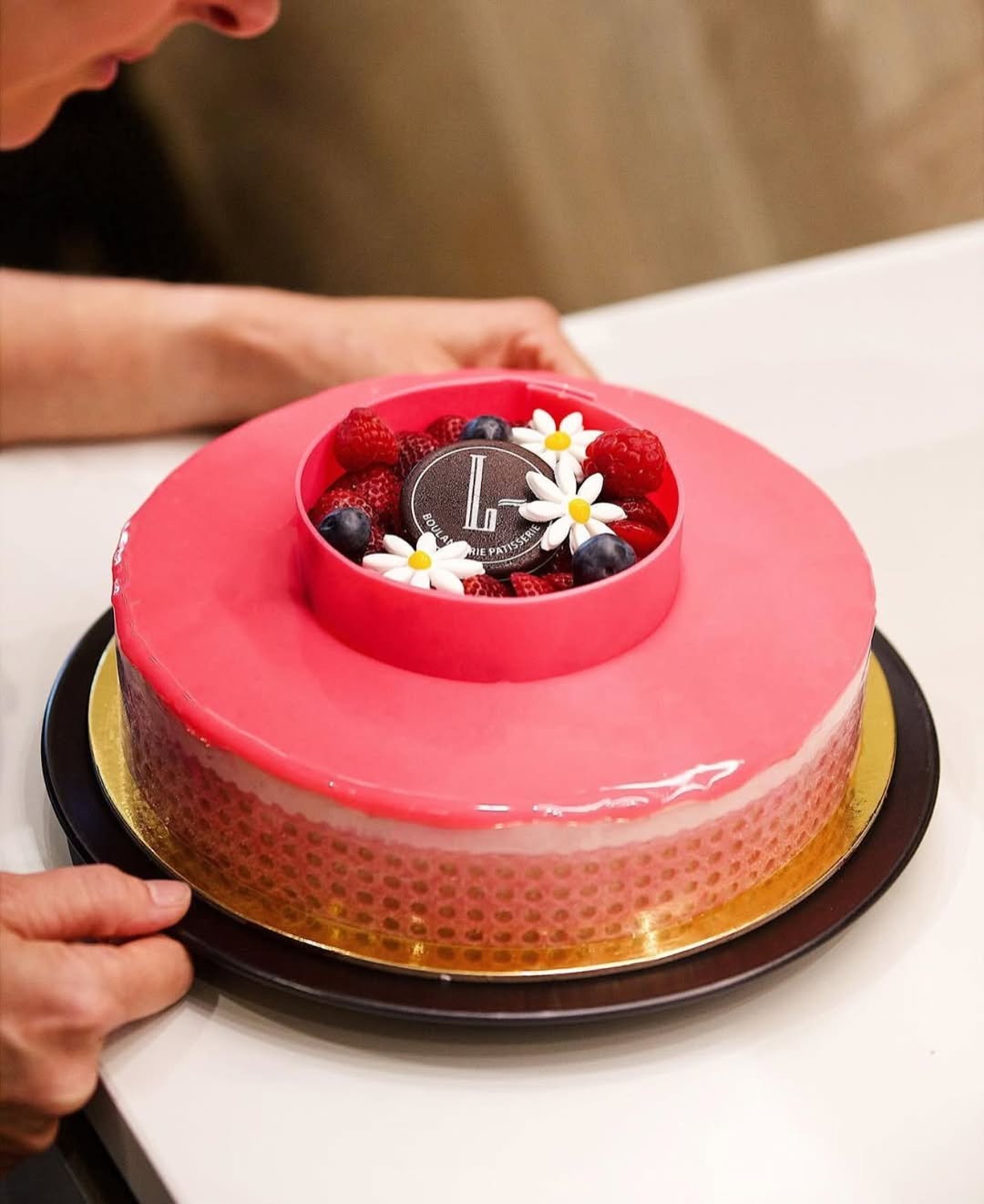 Red cake with fruit and flower decoration and printed logo on chocolate made with chocolate transfer sheets