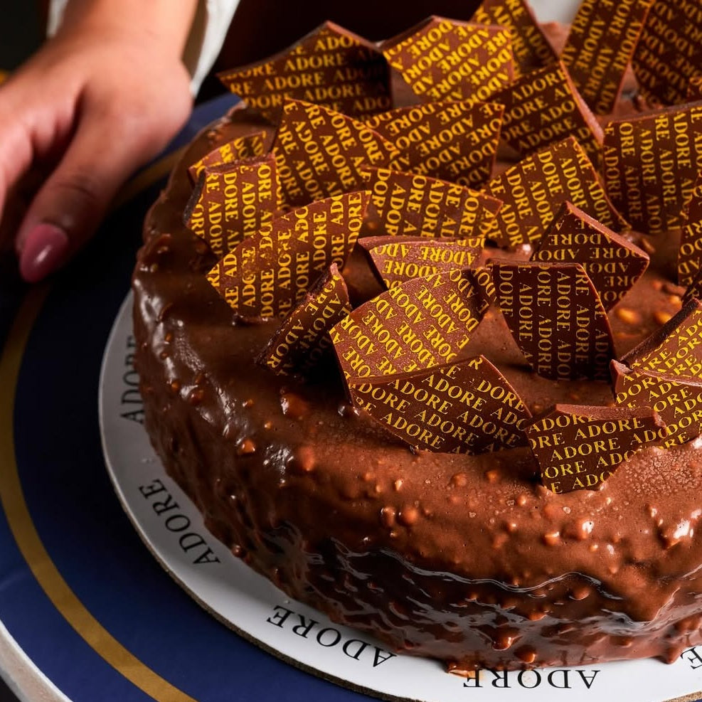 Chocolate cake with ADORE logo decorations printed in gold and made with chocolate transfer sheet